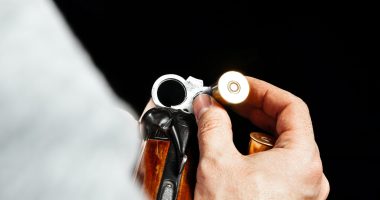 Male hands holding hunting rifle on black background